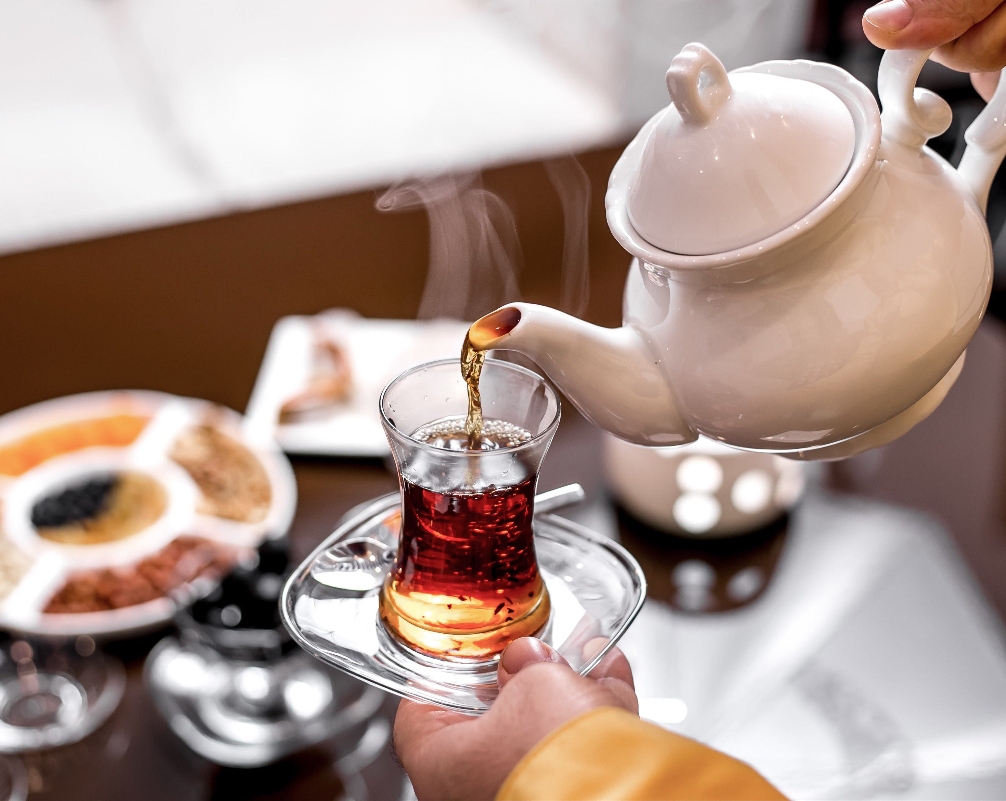 front-view-man-pours-tea-glass-armudu-from-teapot-tea-holds-glass.jpg